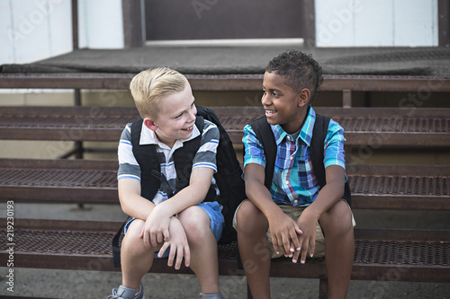 Candid photo of two students talking together at school. Smiling boys having fun together sitting on the stairs enjoying their friendship photo