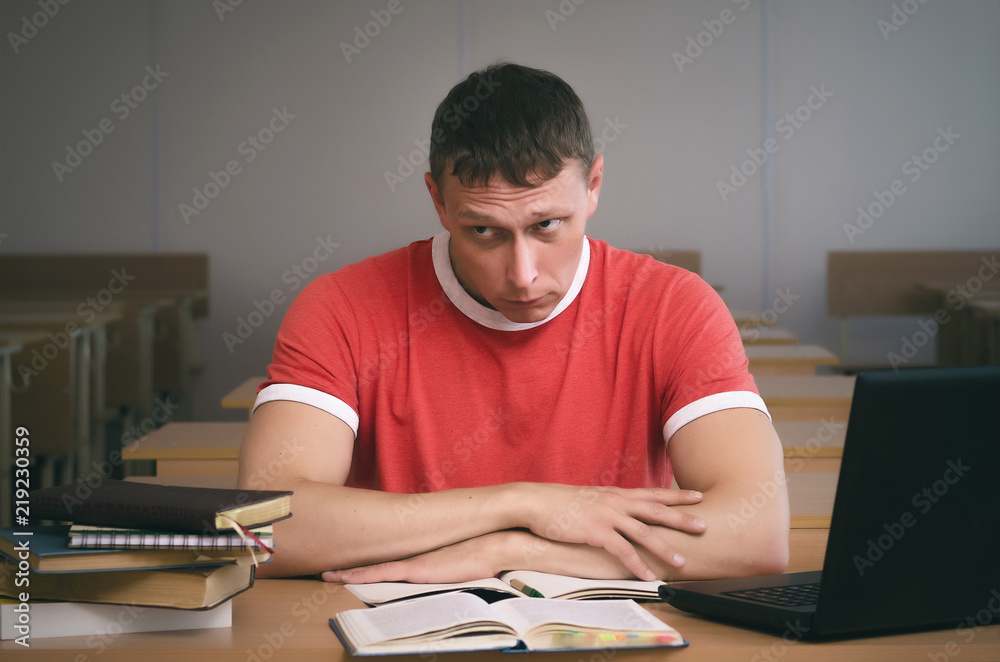 The student is sitting at the table and is looking for excuses for not being ready for the lesson. The student is sitting at the table and is looking for excuses for not being ready for the lesson.