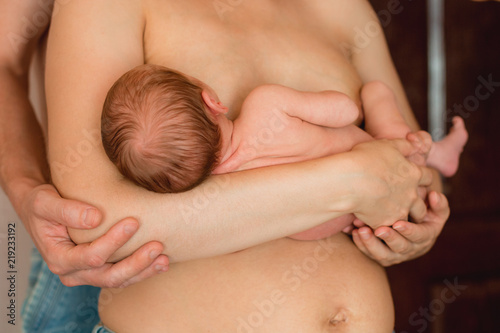 Mother is breast-feeding a newborn baby. Little baby girl breast feeding