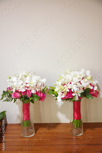 Couple of red rose and white flower bouquet decorating with red pink ribbon on the glass vase