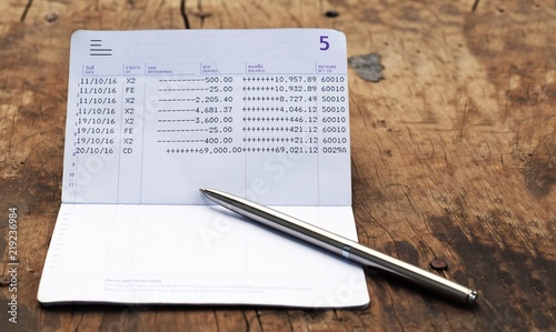 bank account book with silver luxury pen on rustic wood background with copy space