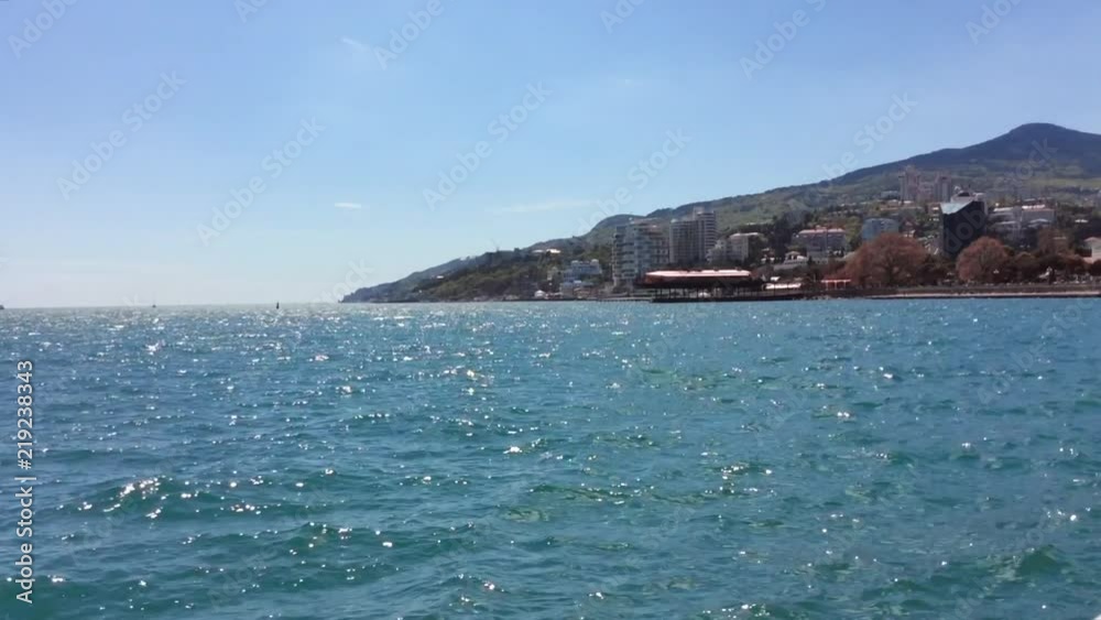 Sparkling sea water and mountain with city in background Sparkling sea water and mountain with city in background