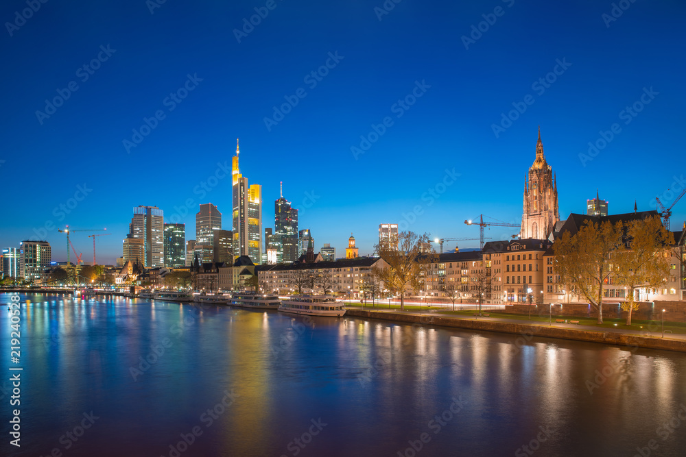 Fototapeta premium View of Frankfurt am Main skyline at dusk along Main river with cruise ship in Frankfurt, Germany