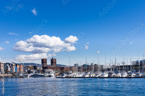 Boats moored at the port where the town hall buildings stand out as seen by Aker brygge, Oslo