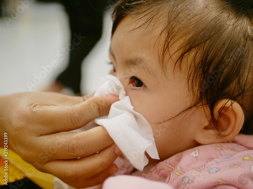 Photography Close up of a mother hand squeezing her daughter running nose - cleanning a baby