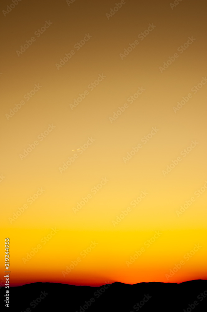 An orange sunset or sunrise shot on portrait orientation. Background  wallpaper photo for a smartphone. Orange and yellow sky, mountain landscape  on horizont. Stock Photo | Adobe Stock