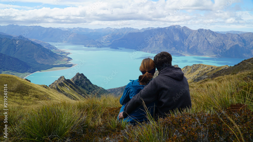 Couple enjoying a view of lake Hawea from Isthmus Peak, New Zealand