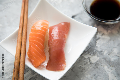 Lachs und Tunfisch Nigiri Sushi mit Sojasauce und Holz Stäbchen auf Porzellan Teller photo