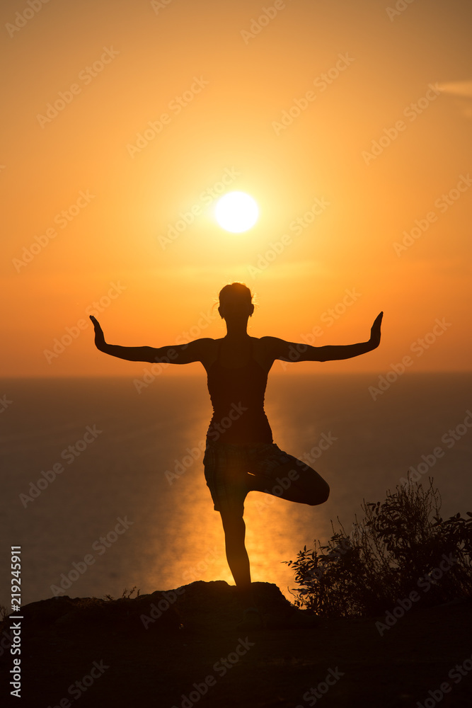 Fototapeta premium silhouette of a woman doing yoga during the sunset 