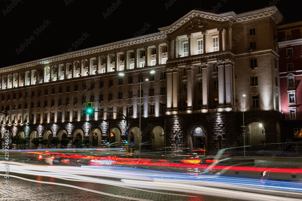 Naklejka premium Building of Council of Ministers in Sofia, Bulgaria. Night view with traffic light trails. Text Council of ministers in Bulgarian on the building