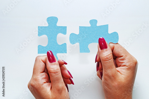 Female hands hold two elements of a puzzle piece on a white background. photo