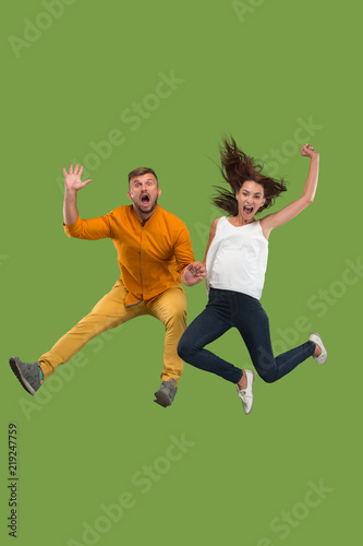Freedom in moving. Pretty young couple jumping against green background
