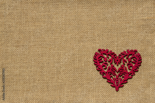 rotes filigranes Herz auf Hintergrund aus Jute