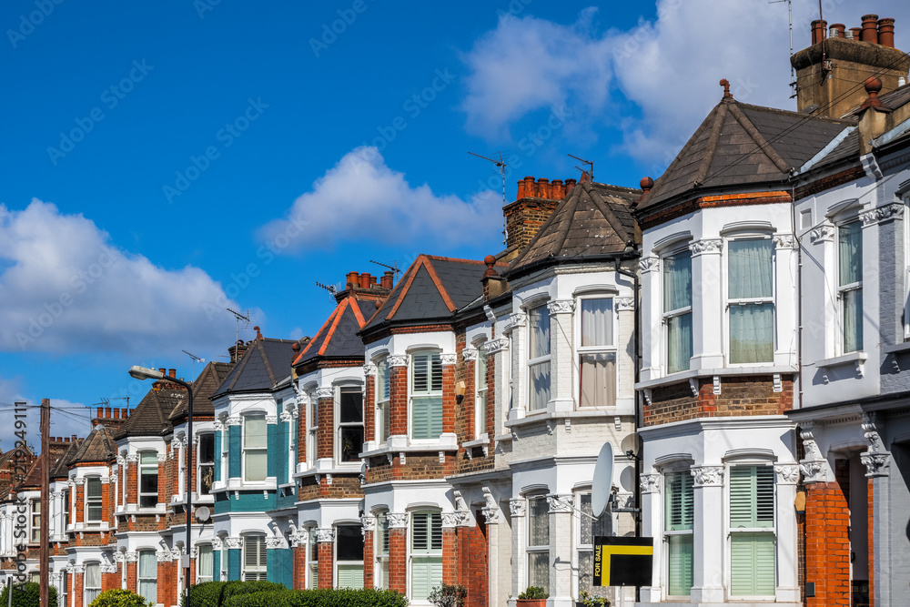 A row of typical British terraced houses in London with an estate agent sign