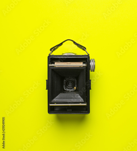 Obraz na plátně black old camera genos from back on green yellow background isolated from above