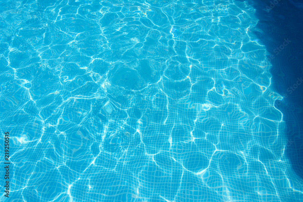 blue water surface with highlights in the pool. the bottom of the smaller tiles. shade canopy on the edge