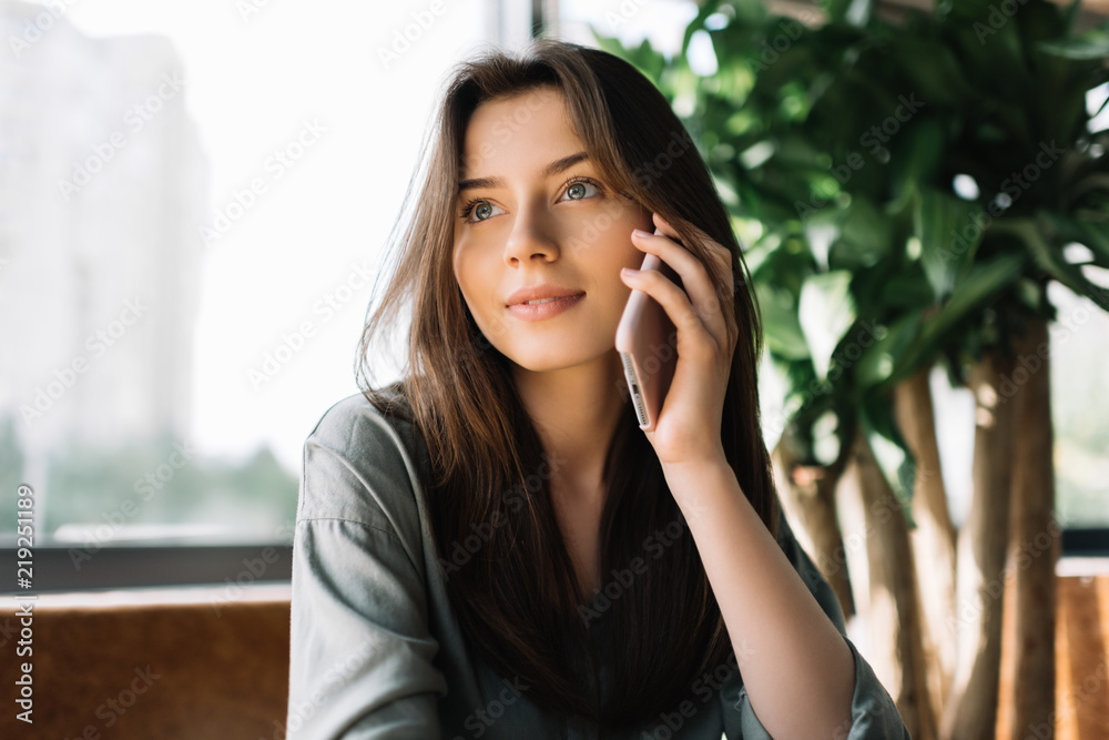 Closeup portrait of attractive caucasian business woman holding smartphone sitting at office. Young beautiful female using mobile phone in modern cafe Closeup portrait of attractive caucasian business woman holding smartphone sitting at office. Young beautiful female using mobile phone in modern cafe