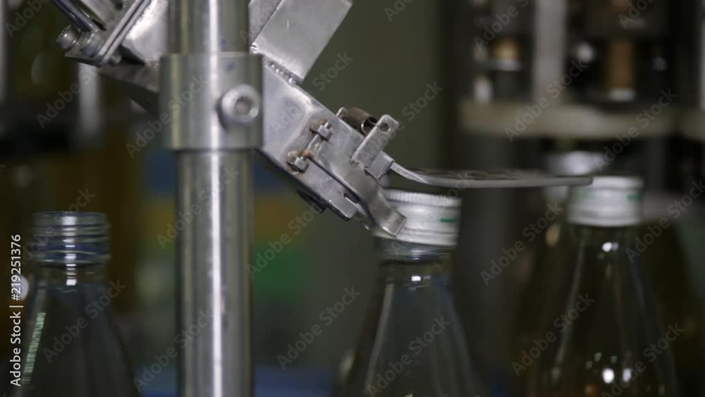 The mechanism of the automatic bottle capping machine. Production of drinking water and beverages. Herbal health drinks manufacturing industry. The mechanism of the automatic bottle capping machine. Production of drinking water and beverages. Herbal health drinks manufacturing industry.