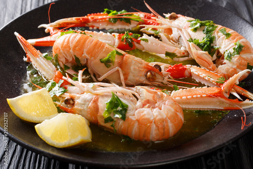 Boiled seafood scampi or langoustine or Norway lobster are served with a fragrant sauce and a lemon close-up. horizontal