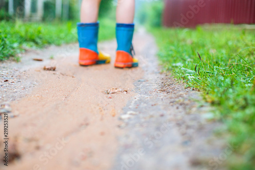 child in rubber boots walking outdoor. child's feet in a rubber boot
