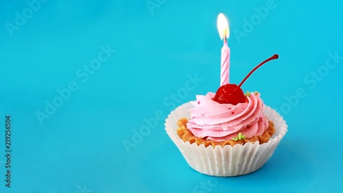 Birthday cake with cherry and burning candle for birthday on blue background