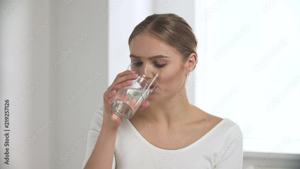 Woman Taking Pill, Drinking Water From Glass In White Interior Woman Taking Pill, Drinking Water From Glass In White Interior