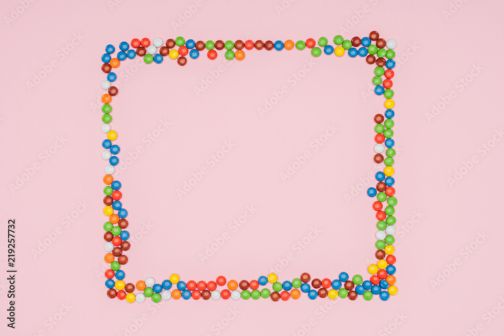 top view of frame of dragee candies isolated on pink