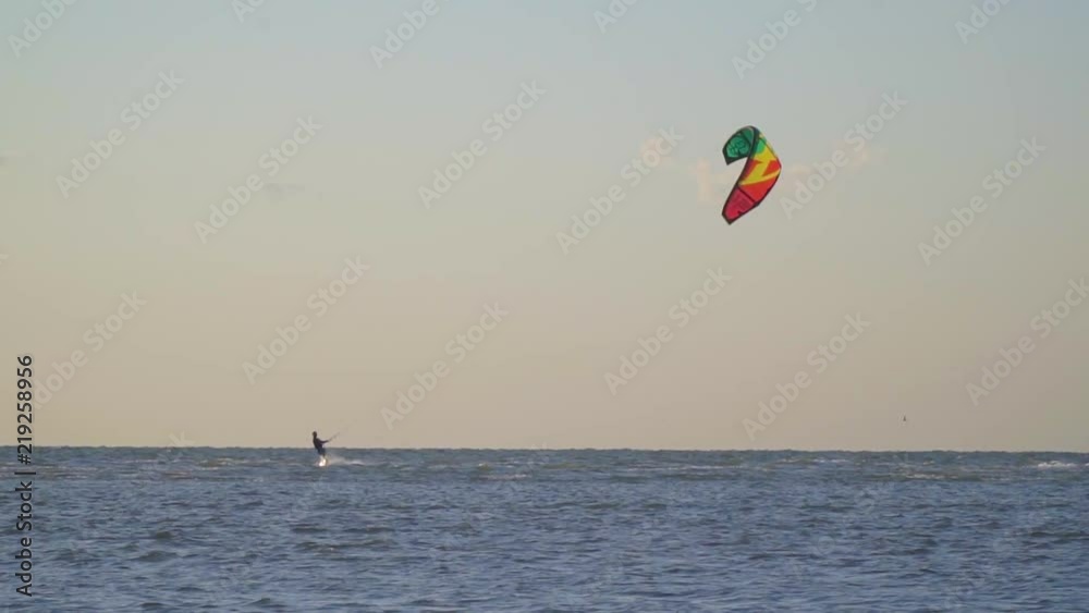 A man is engaged in kitesurfing, a gull is flying across the sky. Slow motion A man is engaged in kitesurfing, a gull is flying across the sky. Slow motion