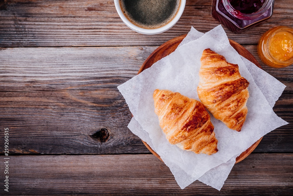 Fototapeta premium Homemade baked croissants with jam and coffee on wooden rustic background