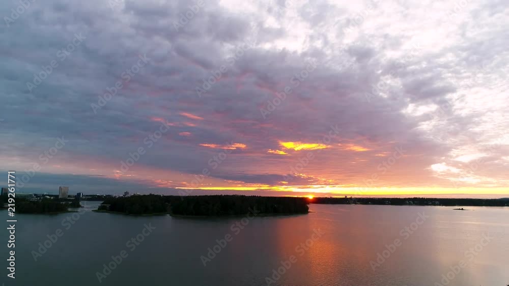 Beautiful 4K sunset. Sun shining behind and bellow clouds low from horizon. Drone flying and rising slowly. Lauttasaari, Mustasaari, Hevossaari, Helsinki capital of Finland. Scandinavia Beautiful 4K sunset. Sun shining behind and bellow clouds low from horizon. Drone flying and rising slowly. Lauttasaari, Mustasaari, Hevossaari, Helsinki capital of Finland. Scandinavia