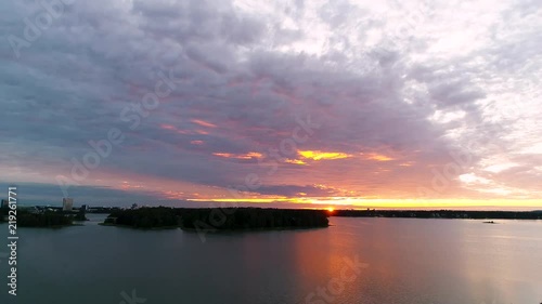 Beautiful 4K sunset. Sun shining behind and bellow clouds low from horizon. Drone flying and rising slowly. Lauttasaari, Mustasaari, Hevossaari, Helsinki capital of Finland. Scandinavia photo