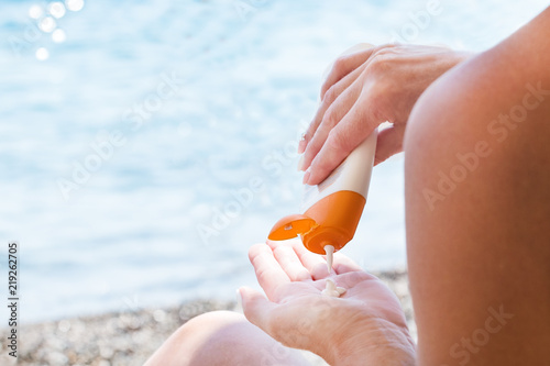 Woman applying protective lotion before sunbathing at beach. Woman applying sun protection lotion. Copy space.