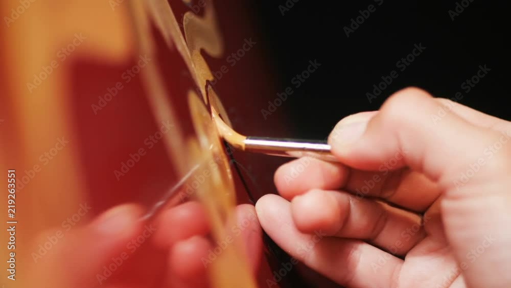 close view painter makes gold drawings on red chiller surface close view painter makes gold drawings on red chiller surface