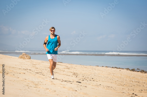 handsome sportsman running on sea shore
