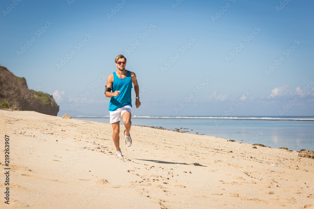 sportsman running on sand beach near sea, Bali, Indonesia