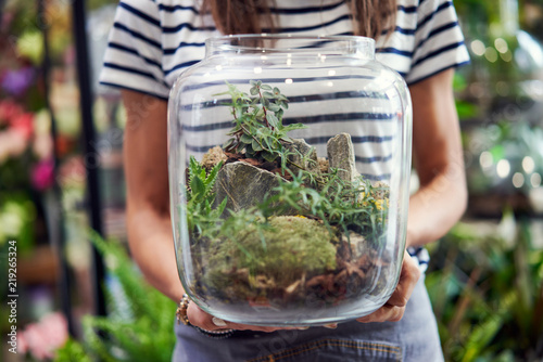 Midsection of florist holding jar terrarium in her shop photo