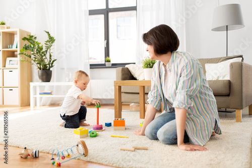 family, child and motherhood concept - happy mother with little baby boy playing developmental toys at home