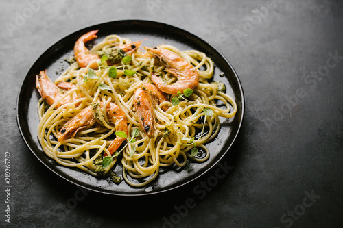 Spaghetti with pesto and prawns served on plate