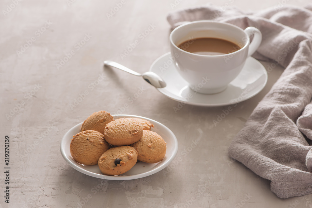 White cup of creamy coffee with butter cookies and stainless teaspoon isolated on white background, clipping path White cup of creamy coffee with butter cookies and stainless teaspoon isolated on white background, clipping path
