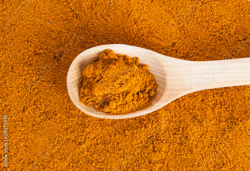 Turmeric powder and fresh turmeric on wooden background.