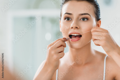 Konstfotografi beautiful young woman using dental floss in bathroom