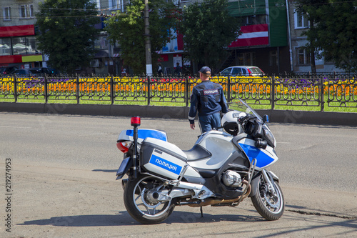 Полицейский офицер дорожной инспекции на дежурстве у мотоцикла.Горизонтально.