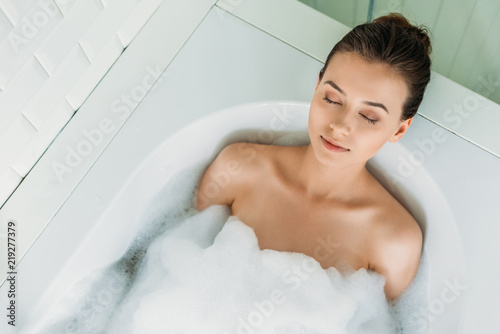 top view of beautiful young woman with closed eyes relaxing in bathtub