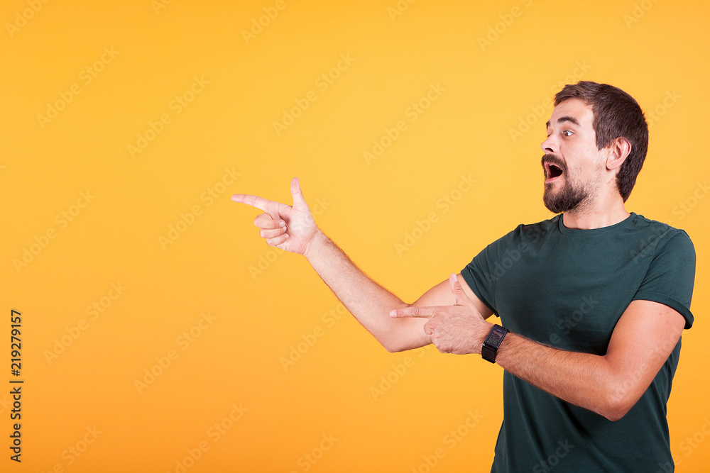 Enthusiasm and expressive man pointing at the copyspace available for your text, promo or advertising. The male is surprised and happy. Orange background Enthusiasm and expressive man pointing at the copyspace available for your text, promo or advertising. The male is surprised and happy. Orange background