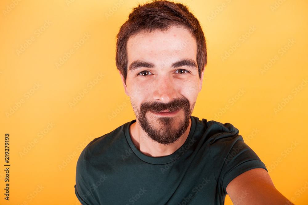 Close up selfie portrait of happy smiling man isolated on yellow background Close up selfie portrait of happy smiling man isolated on yellow background