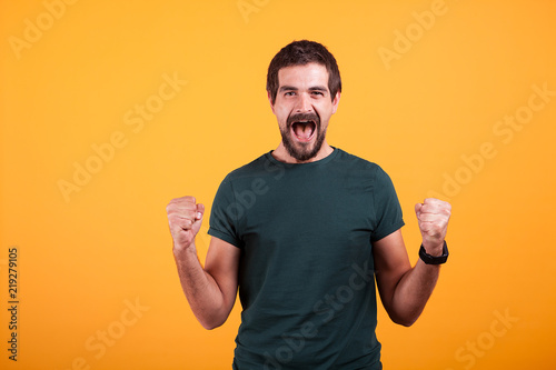 Joyful screaming excited man with his mouth open from emotions on orange yellow background. Portrait of expression and luck