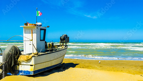 An old fishing boat on the shore of the stormy sea in Pescara, Abruzzo region, Italy – expressive photo without vacationers
