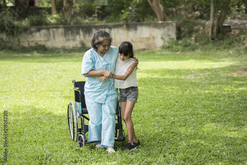 Elderly grandmother in wheelchair with granddaughter in the hospital garden © Johnstocker