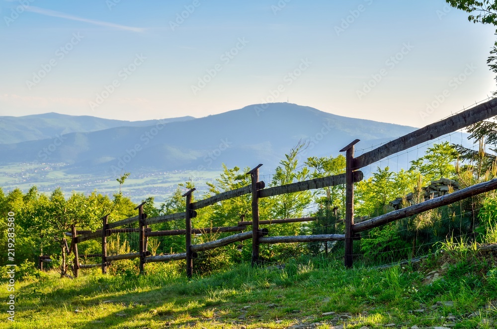 Beautiful rural landscape. Clearing with a wooden fence overlooking the mountains.