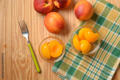 peaches in syrup in the glass bowl with fruit around